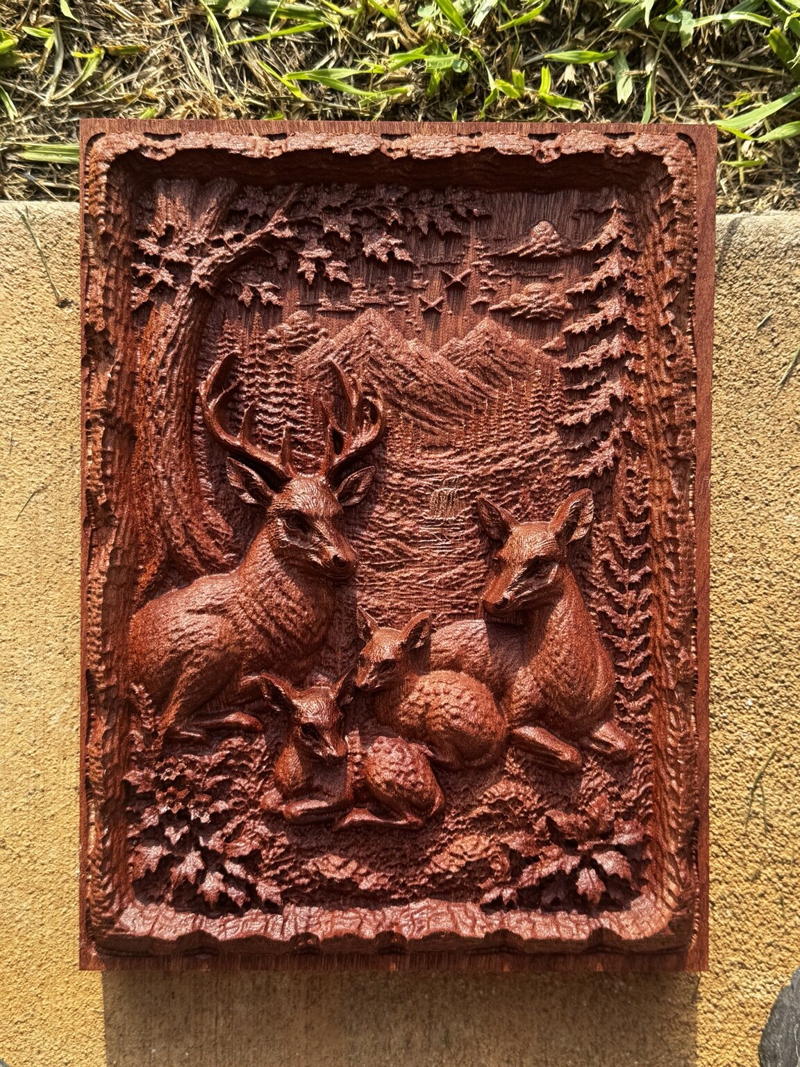 Finished deep relief carving of a deer family in a mountain forest