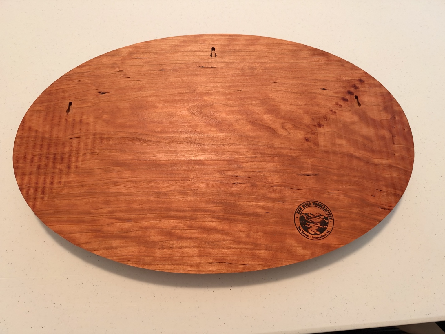 Back of the cherry fox carving showing wood grain, three keyhole mounting slots, and the New River Woodcrafters mark